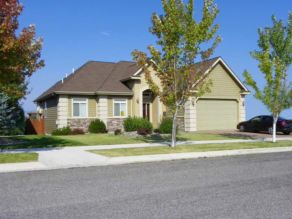 Ranch-style home with a two-car garage on a tree-lined street